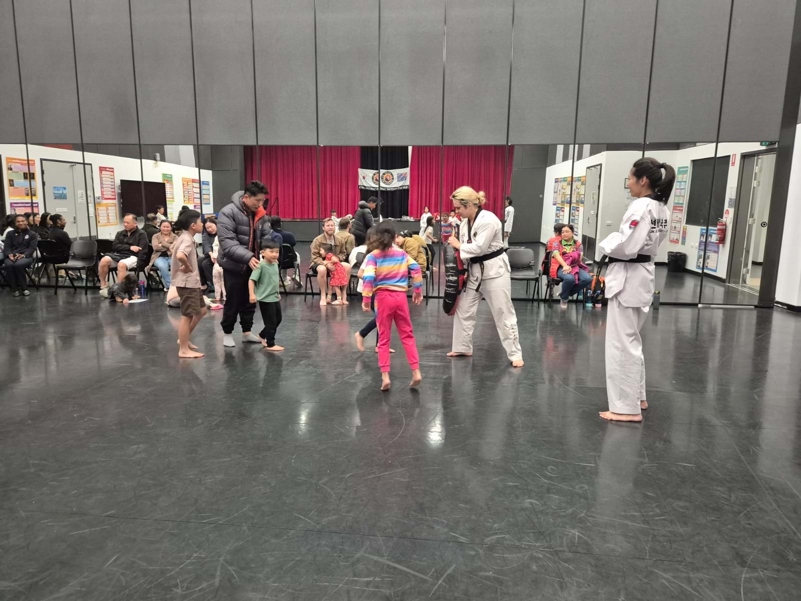 Kids Practice Kicking Techniques on Large Pad at Taekwondo Dojang